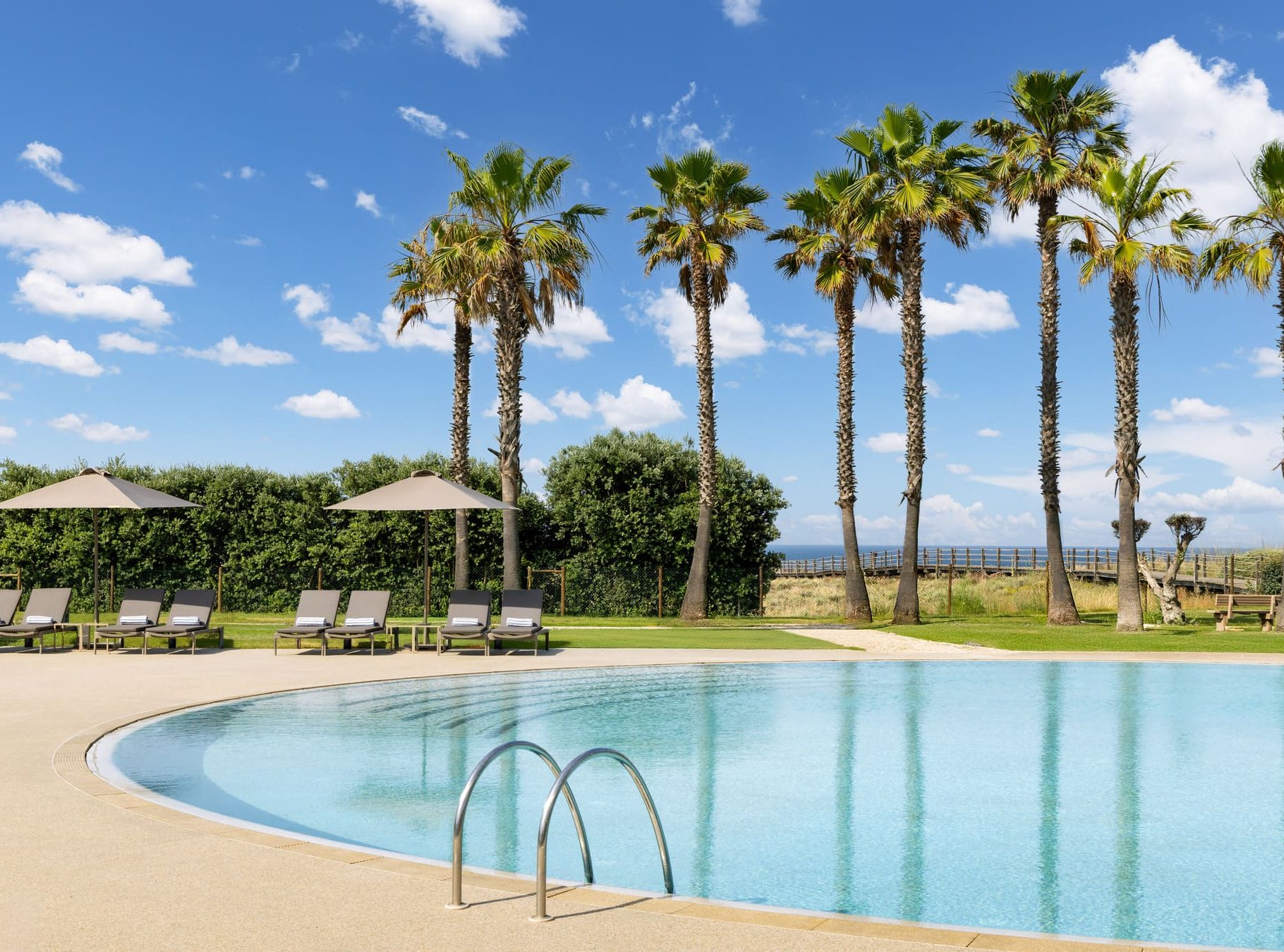 outdoor blue pool featuring sea view of salgados beach and palm trees